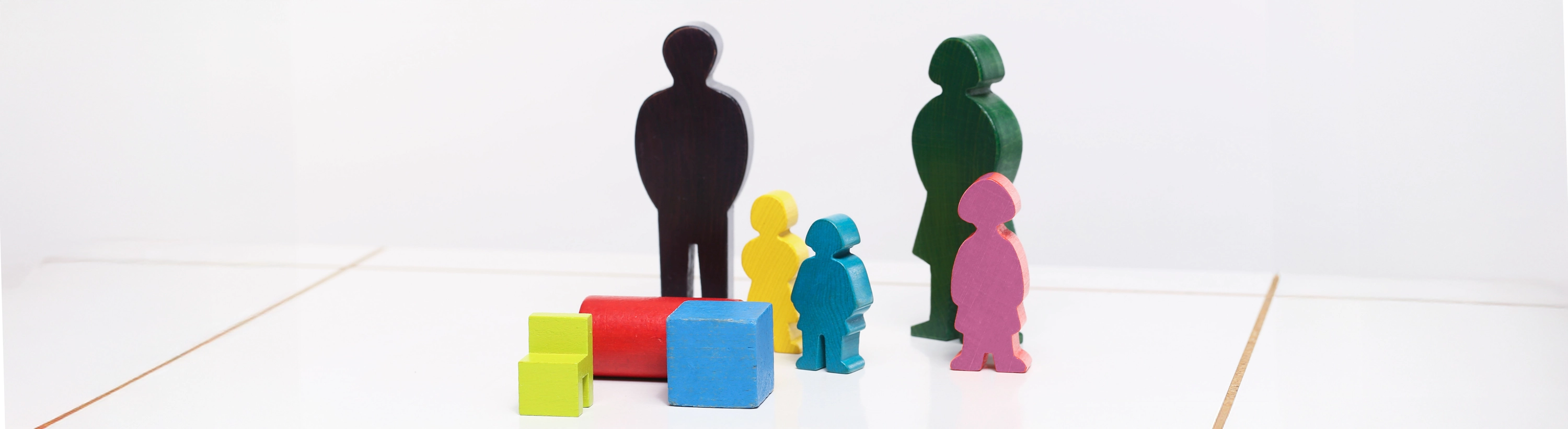 eine Mehrpersonen-Aufstellung mit Holzfiguren und herumliegenden Holzsteinen auf einem Familienbrett